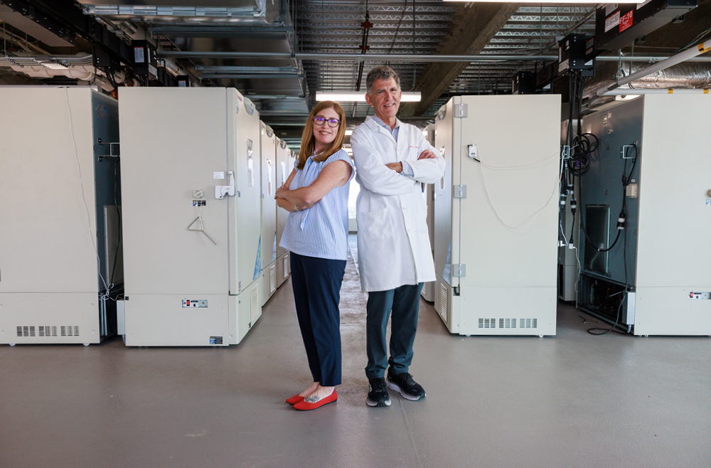 Marylyn Ritchie, PhD, and Daniel Rader, MD, stand back-to-back in front of rows of freezers.
